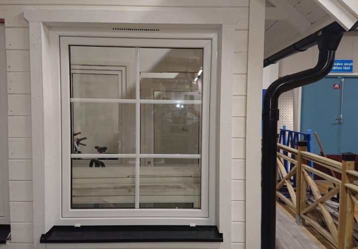 Ett vitkarmat fönster med sex rutor är placerat i en ljus vägg. Inomhus syns ett träräcke och en blå dörr i bakgrunden. Ett vitkarmat fönster med sex rutor är placerat i en ljus vägg. Inomhus syns ett träräcke och en blå dörr i bakgrunden.